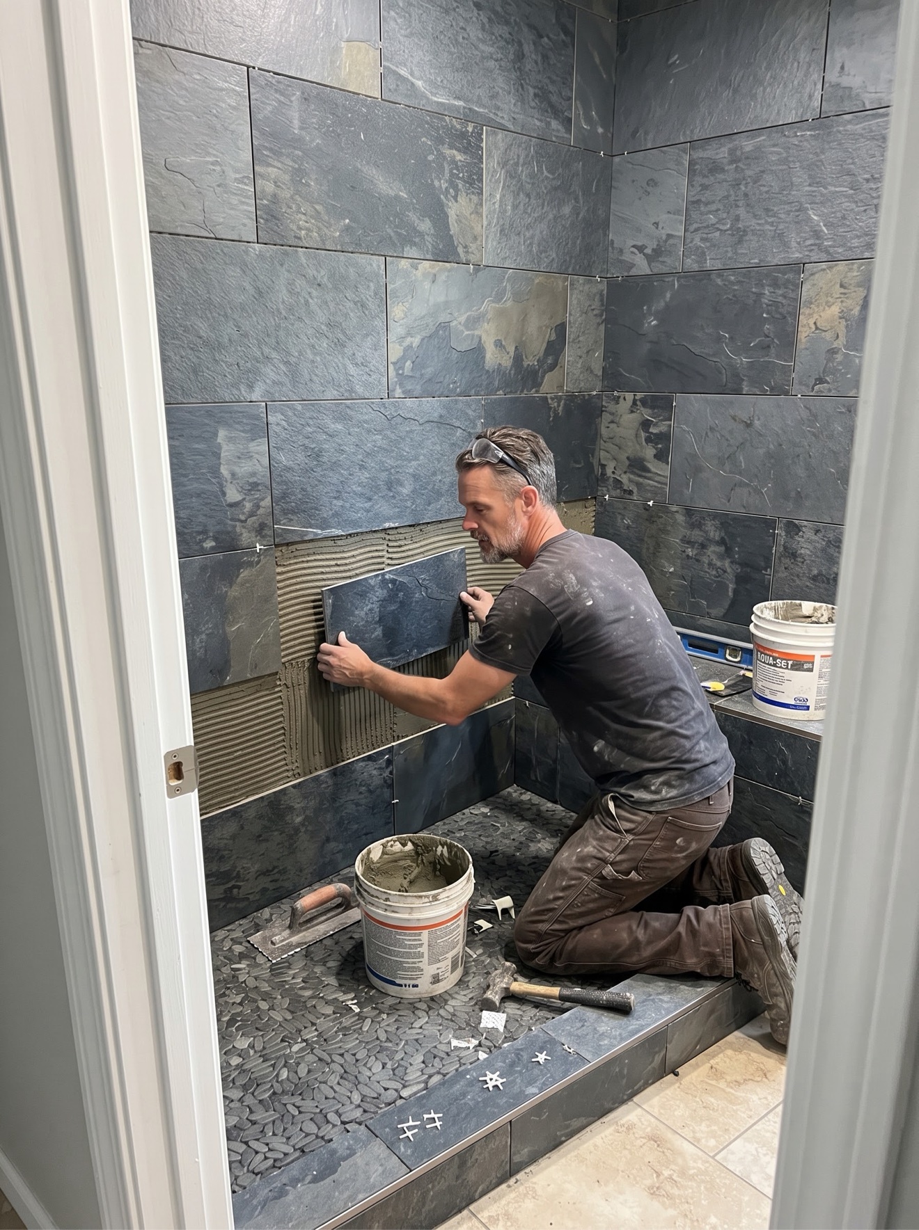 Setting the slate shower walls by hand